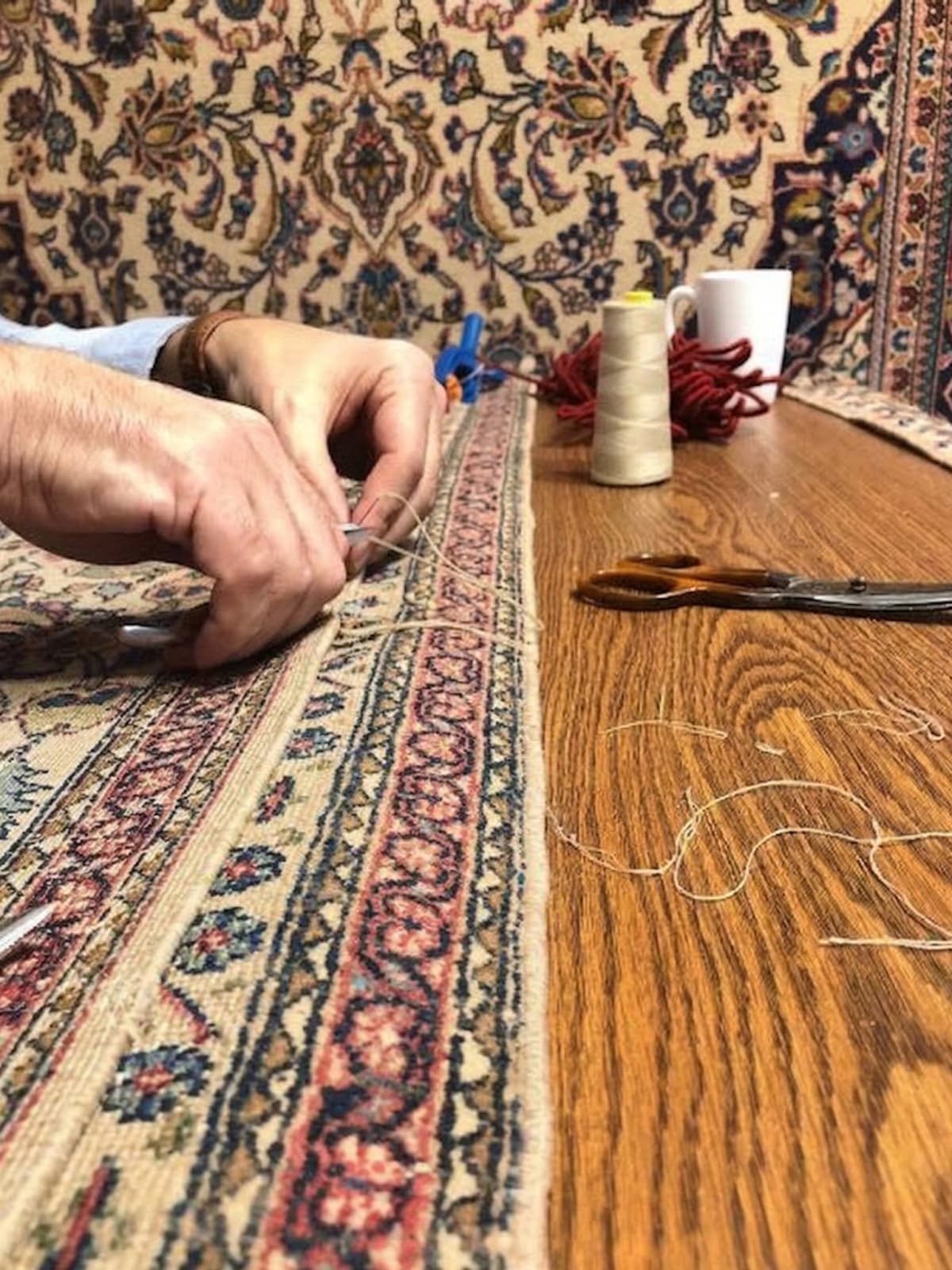 Artisan reweaving damaged knots in an antique Persian carpet